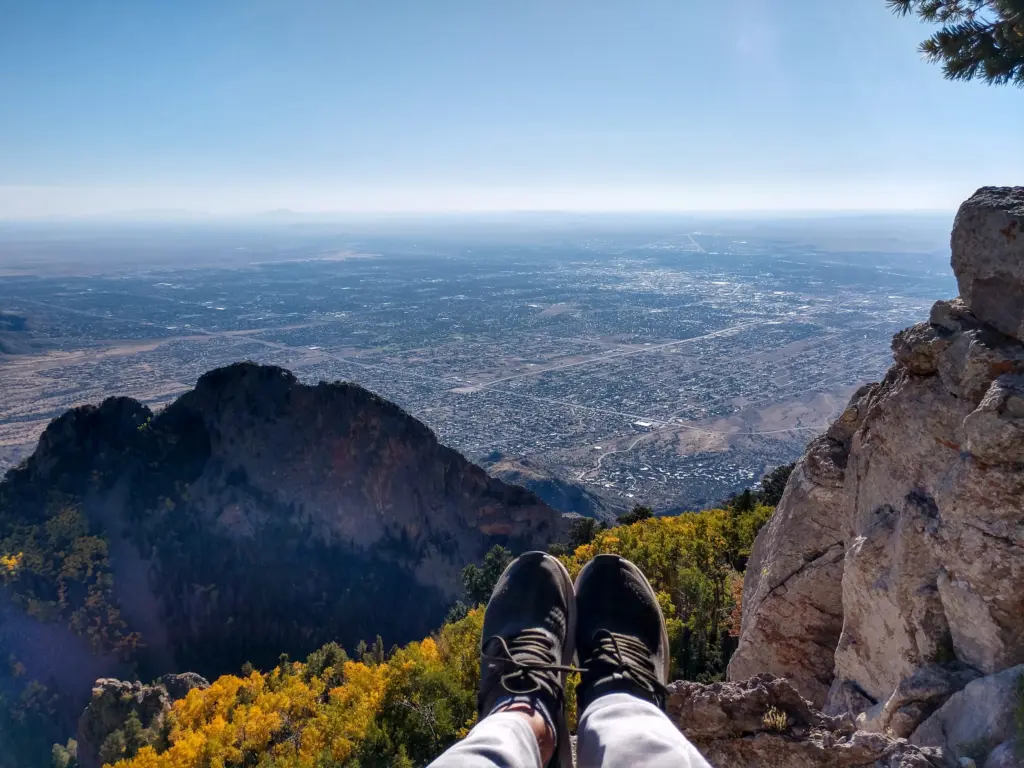 A hiker’s boots resting on a rock high on the Sandia crest, the city far below