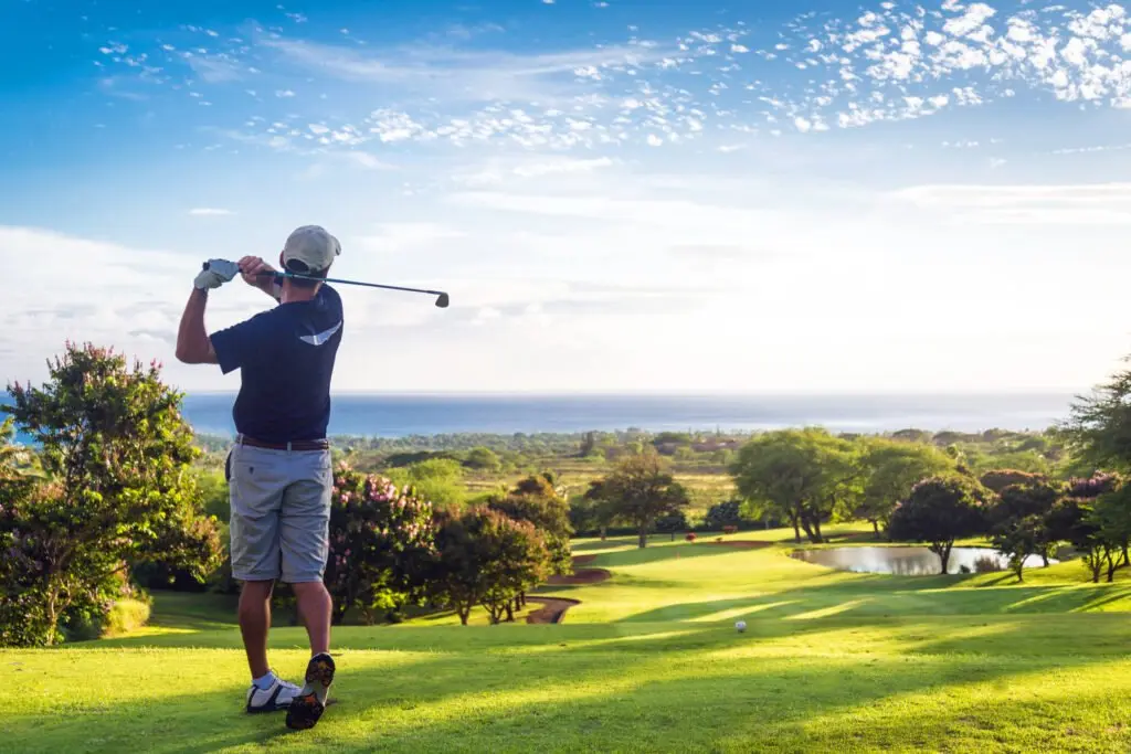 A golfer finishing his swing on a sunny green course
