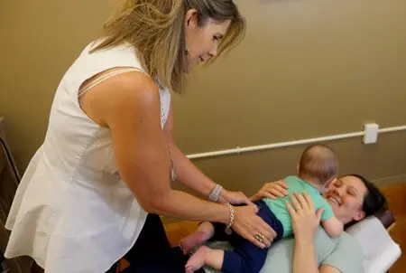 Dr. Marquez gently adjusting a baby who lies on his smiling mother’s chest